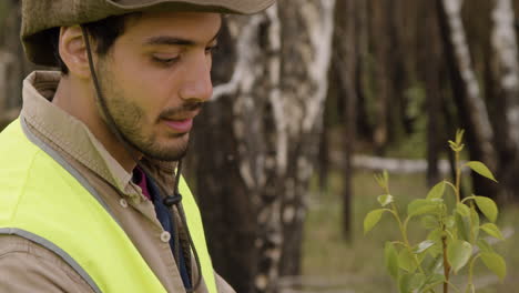 Close-up-view-of-caucasian-man-activist-observing-the-leaves-of-a-tree-in-the-forest