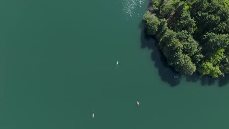 Luftaufnahme-Eines-Langsam-Paddelnden-Kajaks-Auf-Einem-Wunderschönen-Grünen-See-In-Der-Nähe-Immergrüner-Bäume-An-Einem-Heißen-Und-Hellen-Sommertag