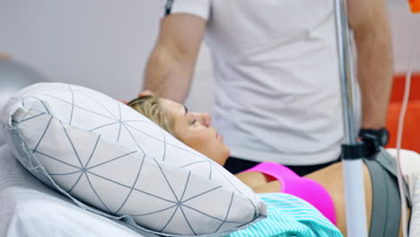 loving man stands at the bed of his pregnant wife. blonde lady breathing deep to relief painful contractions.