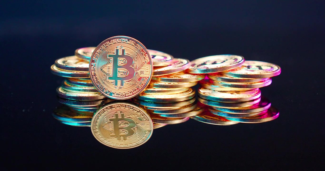 Monete Bitcoin dorate impilate con illuminazione dinamica e colorata