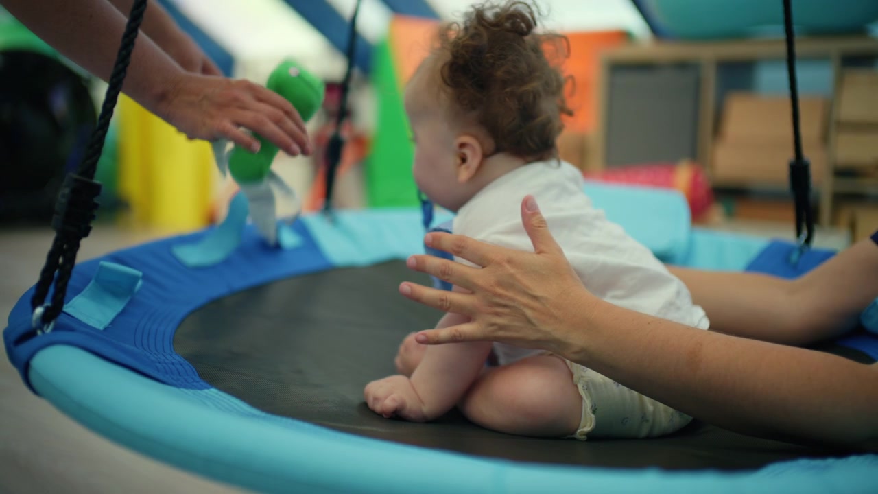 Bebê pequeno participando de terapia de integração sensorial com a assistência de um terapeuta, desenvolvendo habilidades motoras e equilíbrio