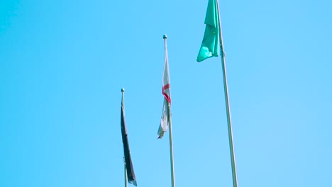 flags of three nations against blue sky