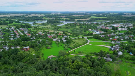 Aerial-dolly-ascends-above-forest-to-suburban-neighborhood-subdivision-around-pond