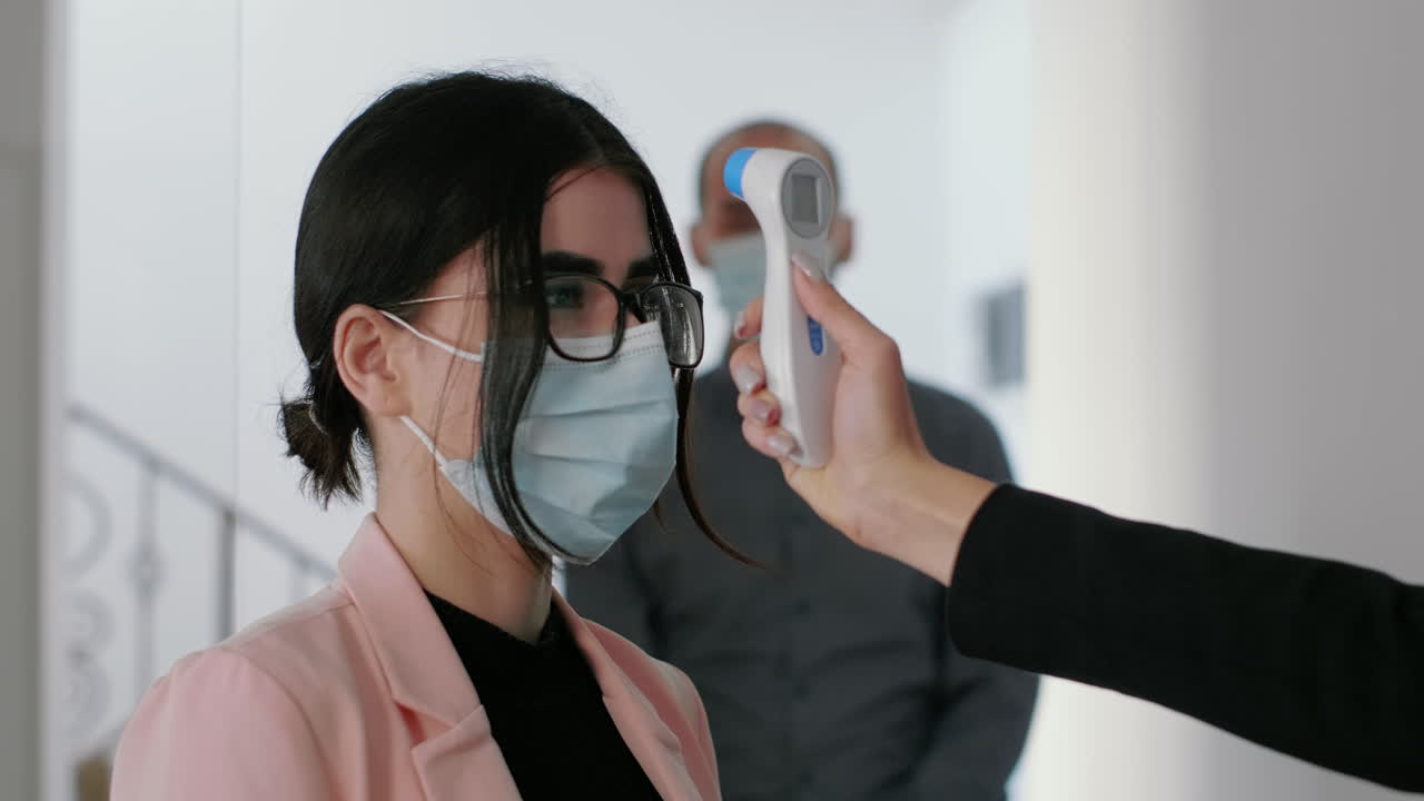 cerrar el freelancer medir la temperatura de los colegas usando un termómetro médico