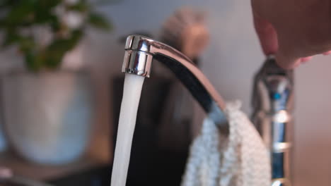 Slow-motion-of-the-faucet-being-turned-on-and-water-flowing