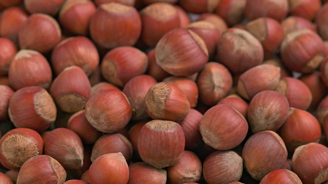looped spinning hazelnuts with the shell close-up full frame background
