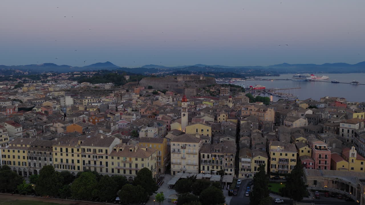 Saint Spyridon Church and rooftops of Old Town Corfu at sunrise, Greece with swallows adding stunning presence, aerial pullback