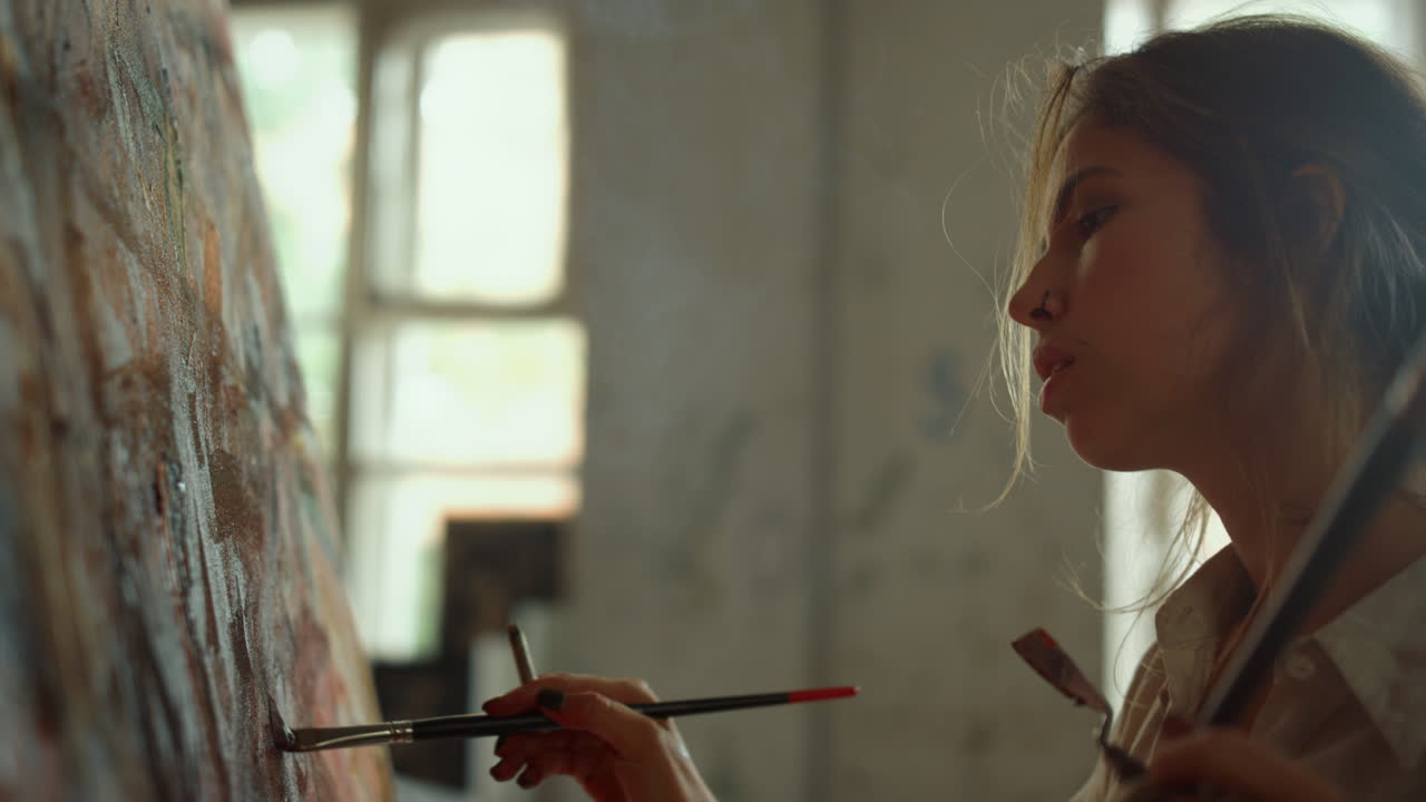 영감을 받은 여성이 실내에서 걸작을 만들고 화가가 스튜디오에서 연기를 내 ⁇ 습니다.