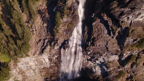 aerial drone footage orbiting counterclockwise around a breathtaking waterfall in springtime in grindewald in switzerland