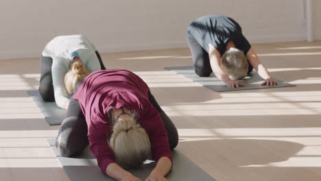 yoga class of mature women exercising healthy meditation practice childs pose enjoying morning physical fitness workout in studio