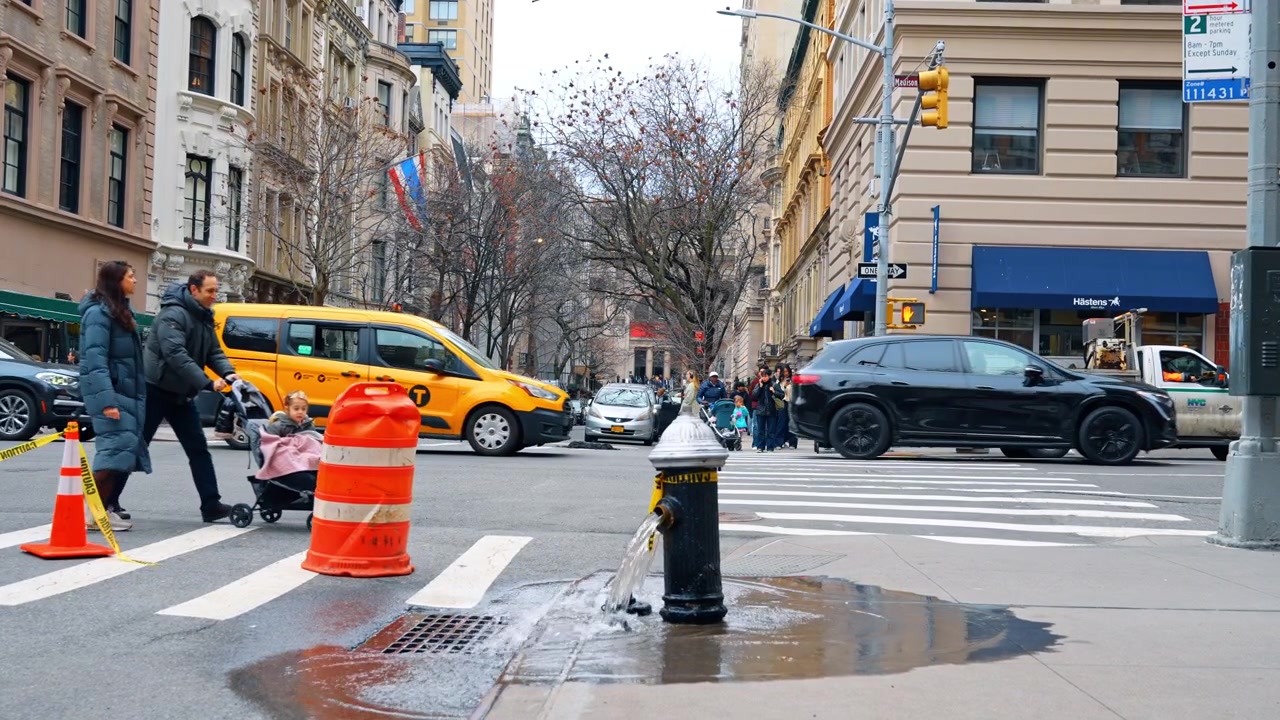 New York, USA, 18 March 2026: Open fire hydrant flushing water on Manhattan street corner. High angle view of water gushing from a fire hydrant into a sewer grate on a NYC street.