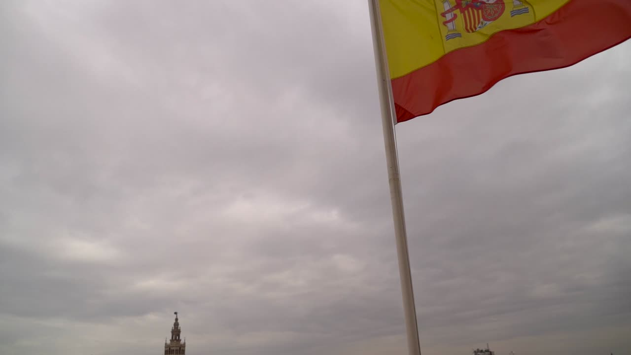 Svelamento del panorama urbano di Siviglia dalla bandiera spagnola in una giornata grigia e nuvolosa