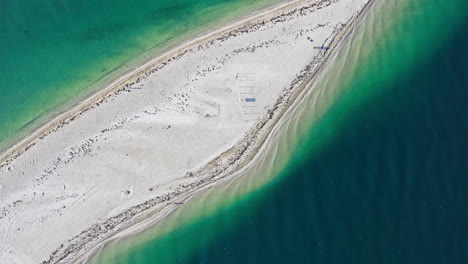 Spinning-aerial-shot-looking-down-on-a-sandy-peninsula-in-tropical-waters