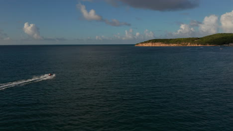 vista lateral aérea de seguimiento turista caucásico en jet-ski a toda velocidad en la puesta de sol en el caribe