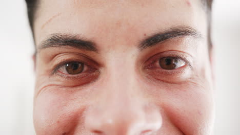 portrait close up of brown eyes of happy biracial man smiling at home, slow motion