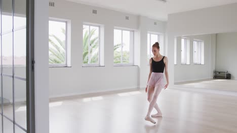 bailarina de ballet caucásica practicando ballet durante una clase de baile en un estudio brillante