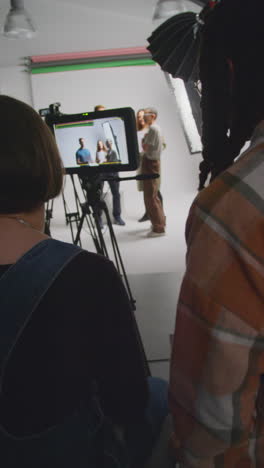 video vertical de actores con guiones en ensayo rodando película o video en estudio con directora y equipo de filmación y viendo en el monitor 2