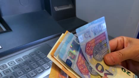 una persona retira billetes de euro de un cajero automático y los cuenta. una mujer retira dinero de una máquina bancaria.