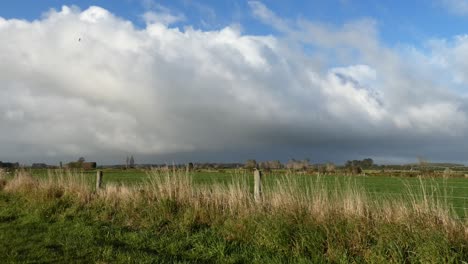 Change-in-early-morning-weather-is-apparent-as-rain-clouds-gather-above-lush-farmland-at-golden-hour---Canterbury,-New-Zealand