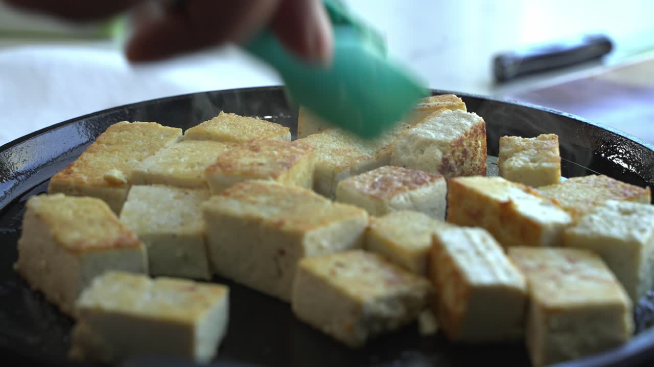 Tofu fritto in primo piano, ingredienti speciali per cucinare un pasto: due lattine di fagioli, riso, platano, avocado, cipolla rossa e coriandolo