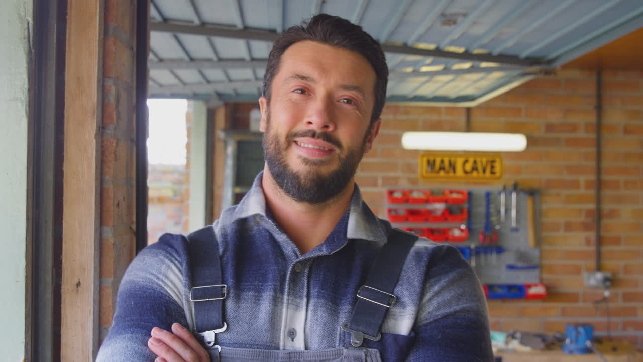 Ritratto di uomo sorridente che indossa una tuta da lavoro nel laboratorio casalingo del garage.