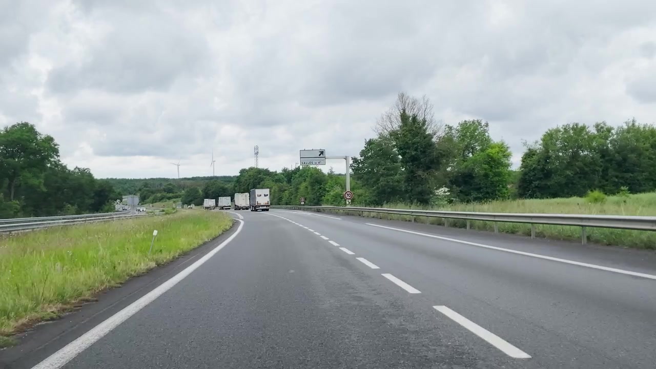 Una telecamera frontale riprende camion semirimorchio che guidano lungo un'autostrada attraverso la verde campagna francese.
