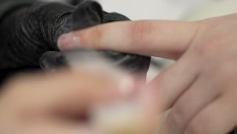 manicurist master shaping and files short nails and performs a manicure on a teenager