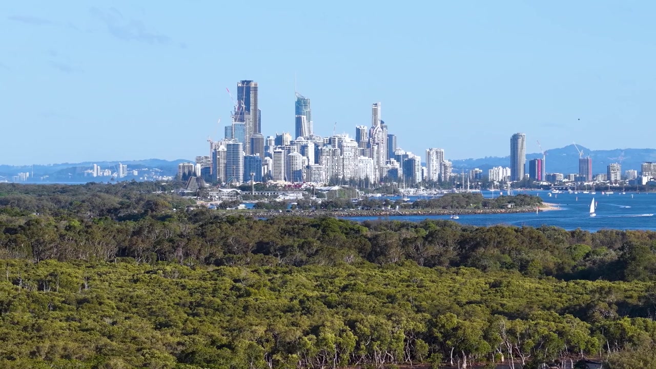 Bredt statisk skud af Gold Coast skyskrabere over vand og kystskov i Queensland, Australien