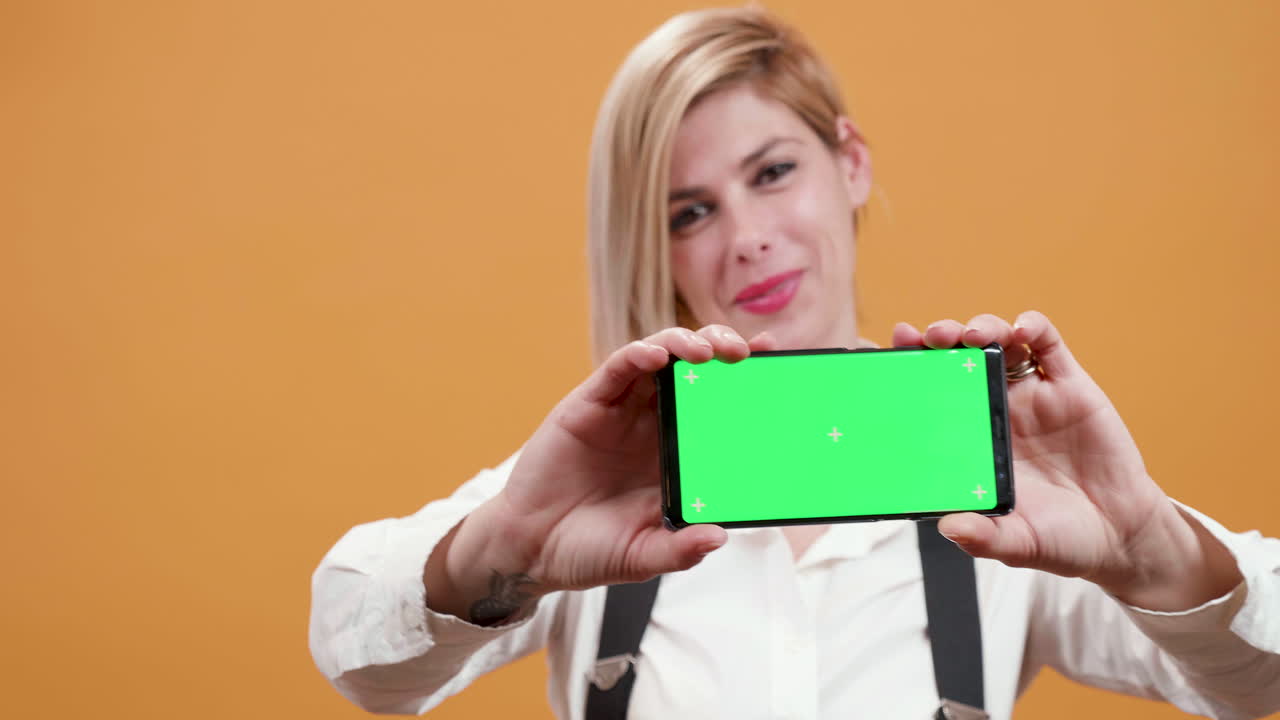 mujer sosteniendo un teléfono inteligente con pantalla verde