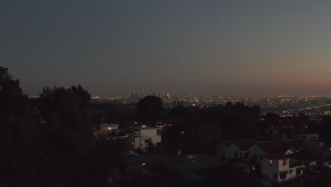 Over-Hollywood-Hills-at-Night-with-view-on-Downtown-Los-Angeles-Skyline,-Aerial-Establishing-Shot,-slow-Dolly-in-forward