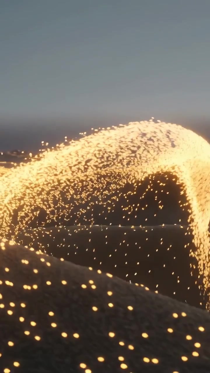 Video verticale: Luce che emerge da sinistra facendo scintillare un nastro dorato su una duna costiera al tramonto, lasciando cadere braci