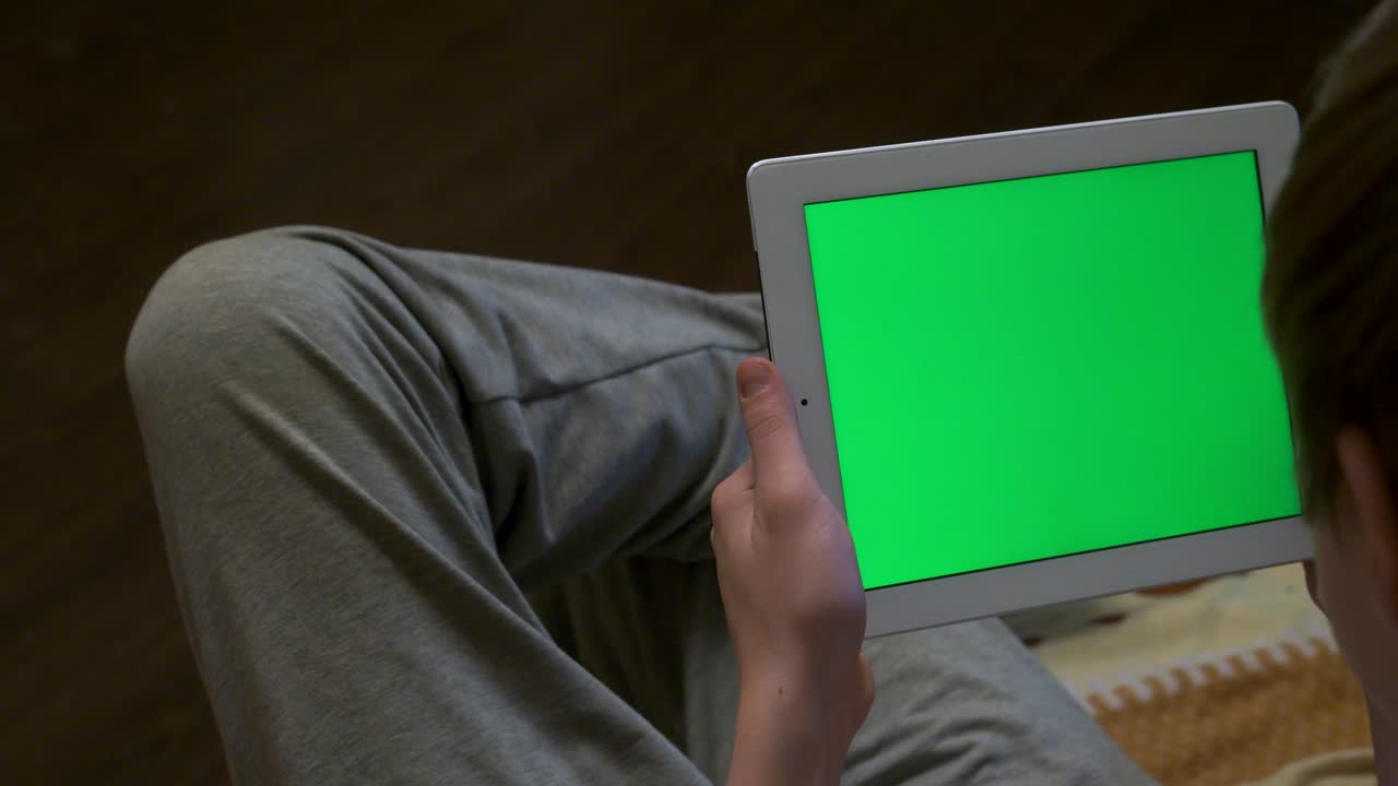 Person holding a tablet with a green screen