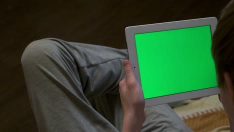 persona que sostiene una tableta con una pantalla verde