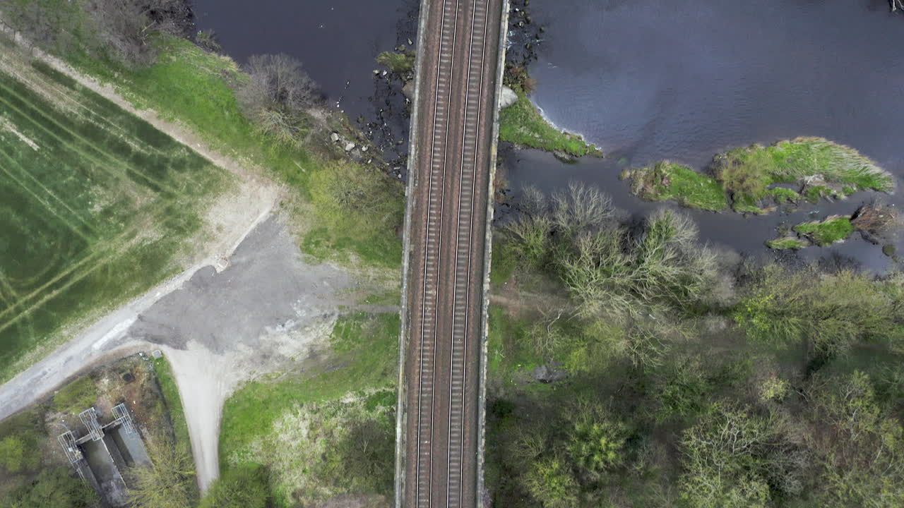 вид с высоты птичьего полета на железнодорожные пути, пересекающие реку в йоркшире, англия, с утками, садящимися на воду