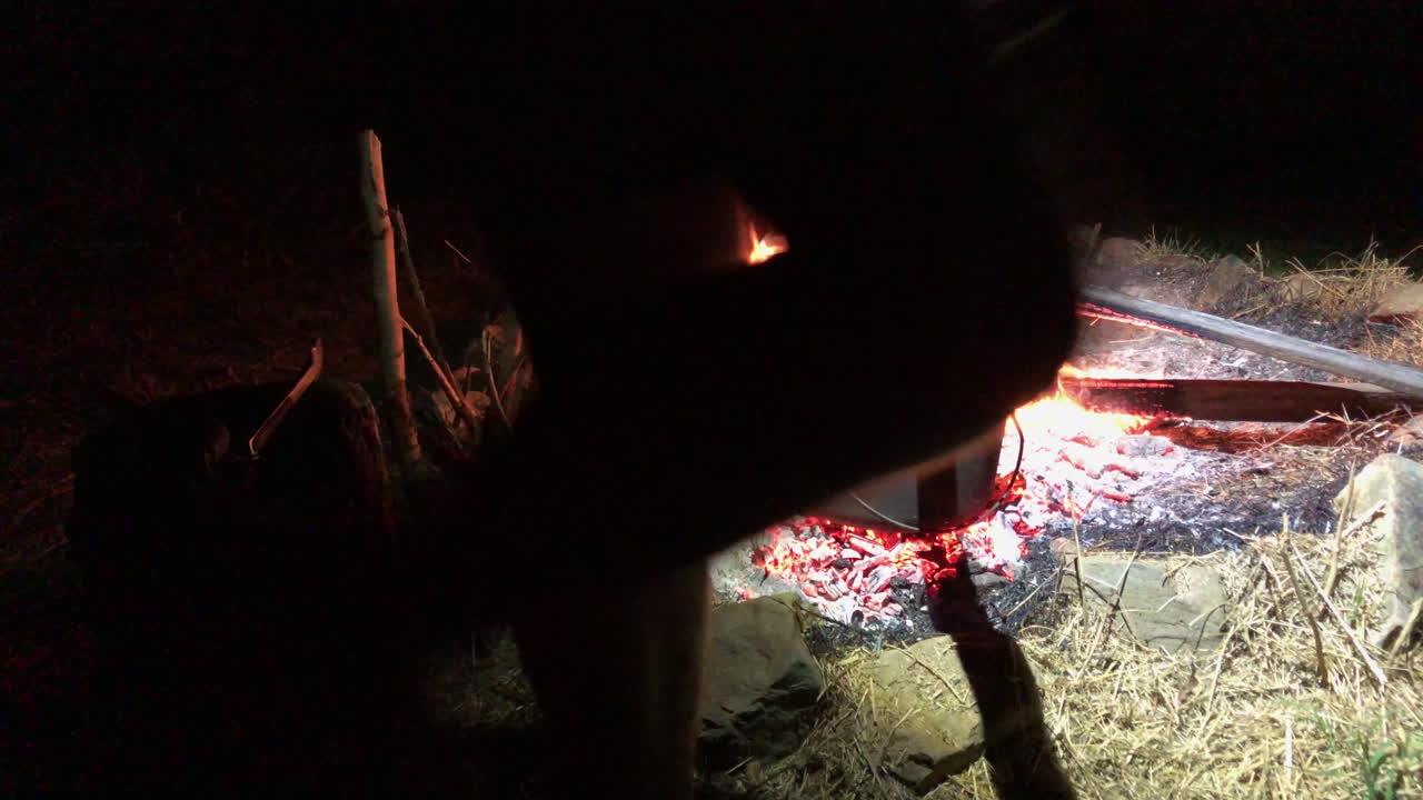 Man Tends Camp Oven Hot Coals with Shovel on Outback Campfire HANDHELD