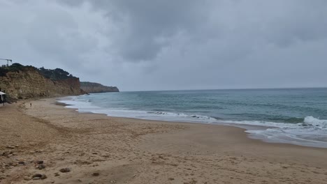 The-shot-is-made-at-Praia-Dona-Ana,-8600-500-Lagos,-Portugal-in-March-on-a-cloudy,-rainy-day-facing-the-sea-with-rock-formations,-and-the-beach-in-the-shot