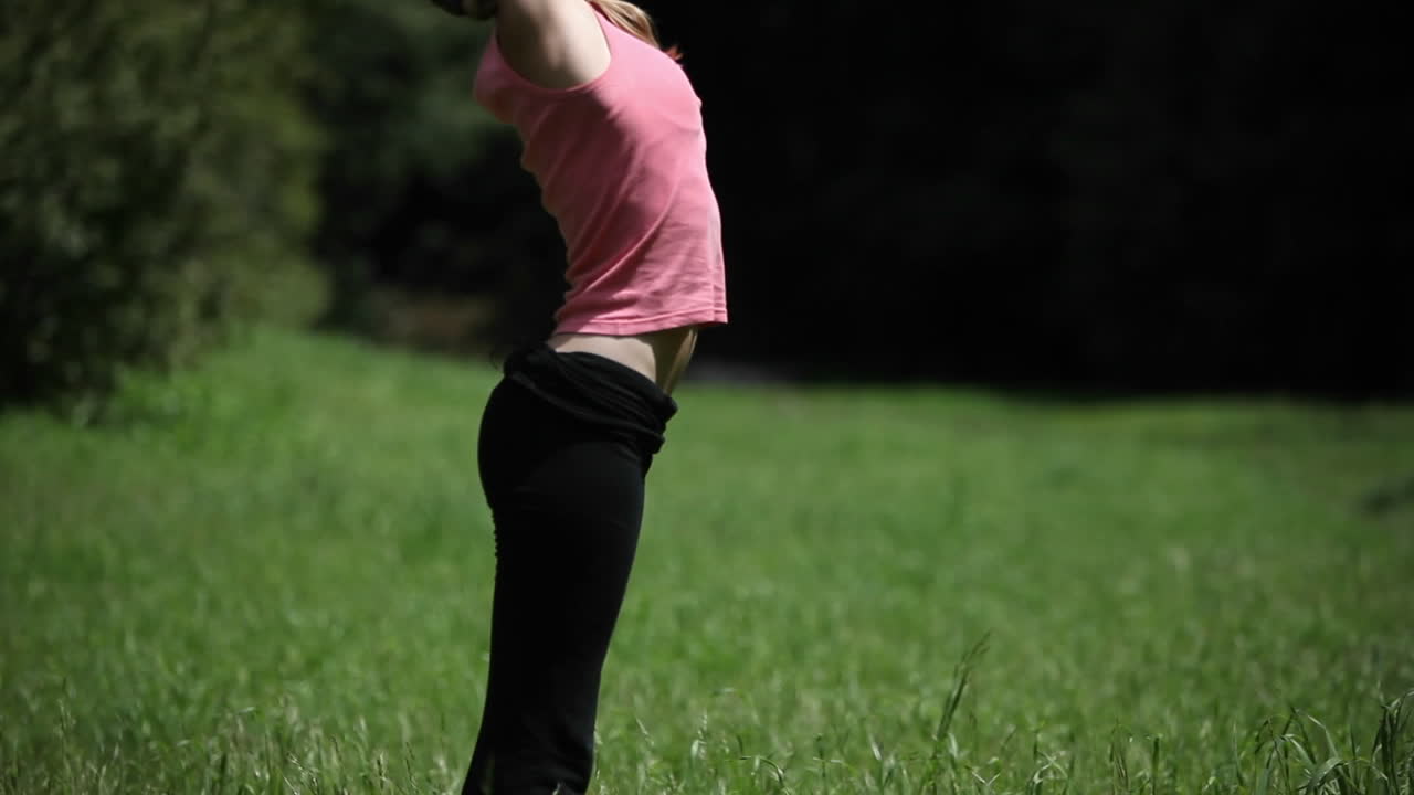 una mujer hace posturas de yoga afuera en la hierba