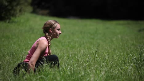 a woman does yoga poses outside in the grass