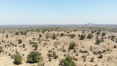 Toma-Aérea-De-Tierra-Seca-Y-árida-En-Jharkhand-Con-Muy-Menos-árboles-Y-Montañas-Al-Fondo.