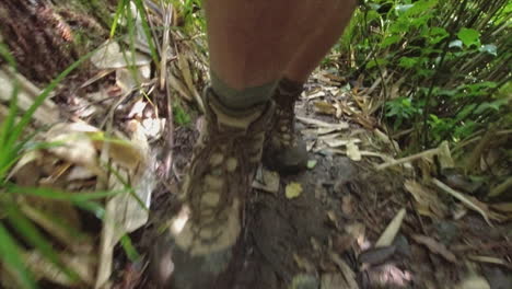 POV of man&#039;s boots hiking on narrow muddy jungle trail in Nicaragua