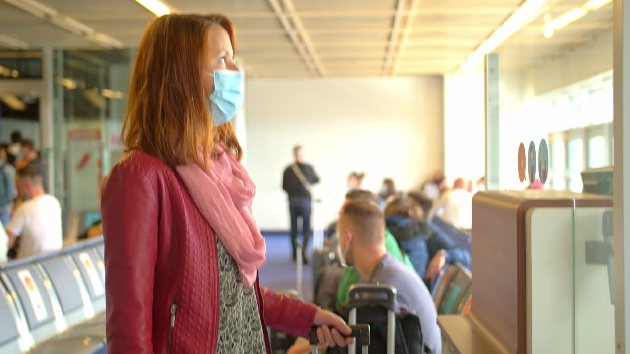 Young redhead woman wearing a face mask waiting to board a commercial flight during the Covid 19 Restrictions