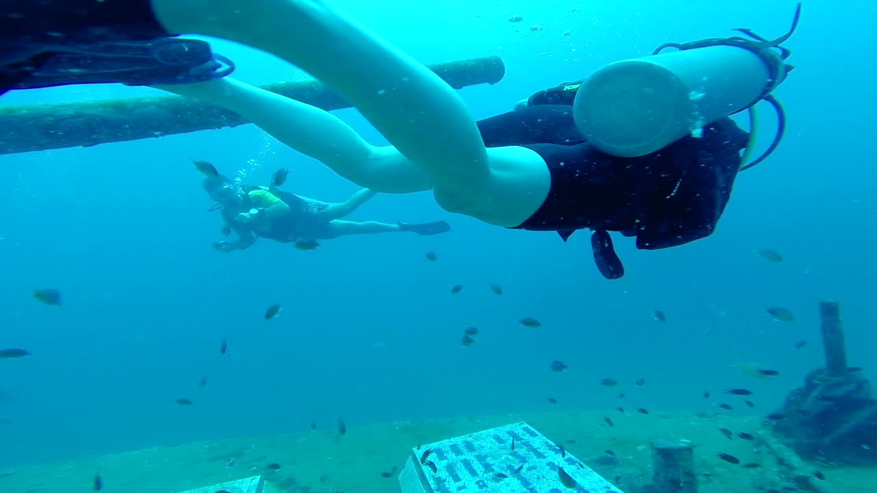 Female scuba diver swimming around ship wreck turret in Thailand (slow motion)