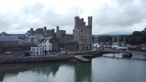 ancient caernarfon castle welsh harbour town aerial view medieval waterfront landmark low angle right orbit