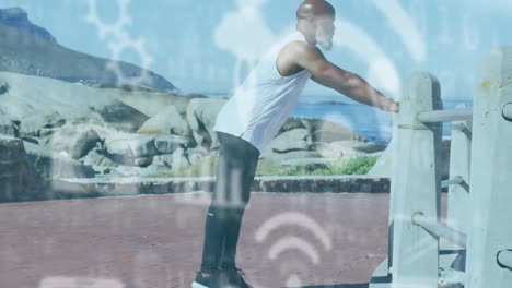 Animation-of-media-icons-over-senior-african-american-man-exercising-at-beach