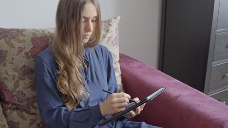 Konzentriertes-Mädchen-Mit-Langen-Haaren,-Das-Mit-Digitalem-Bleistift-Auf-Einem-Tablet-Entwirft