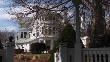 A-Picturesque-Mansion-Sits-Behind-A-White-Fence-And-Gate