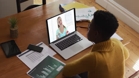 mujer afroamericana que usa una computadora portátil en una videollamada con una colega que trabaja desde casa
