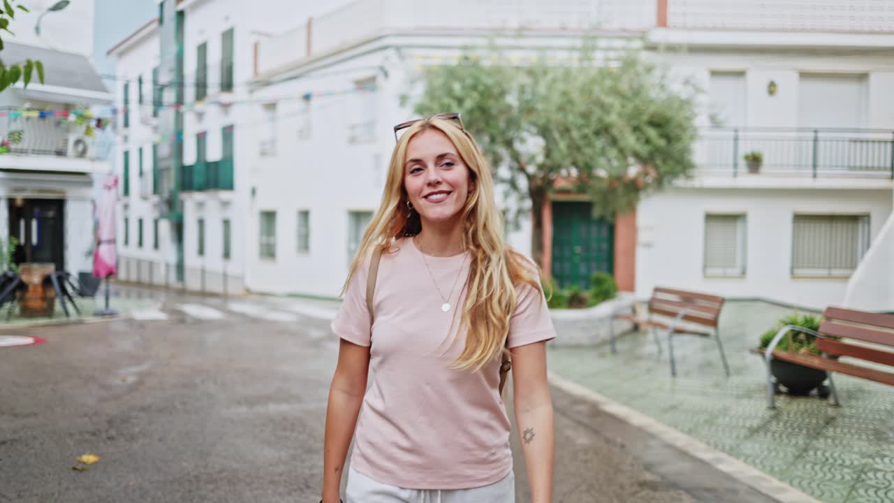 Giovane donna felice che cammina e sorride per una strada affascinante di città.