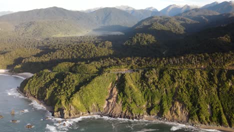 Asombrosa-Vista-Aérea-Del-Paisaje-Salvaje-De-La-Costa-Oeste-De-La-Selva-Tropical-Y-La-Costa-Con-Acantilados,-Punta-De-Los-Caballeros,-Isla-Del-Sur,-Nueva-Zelanda