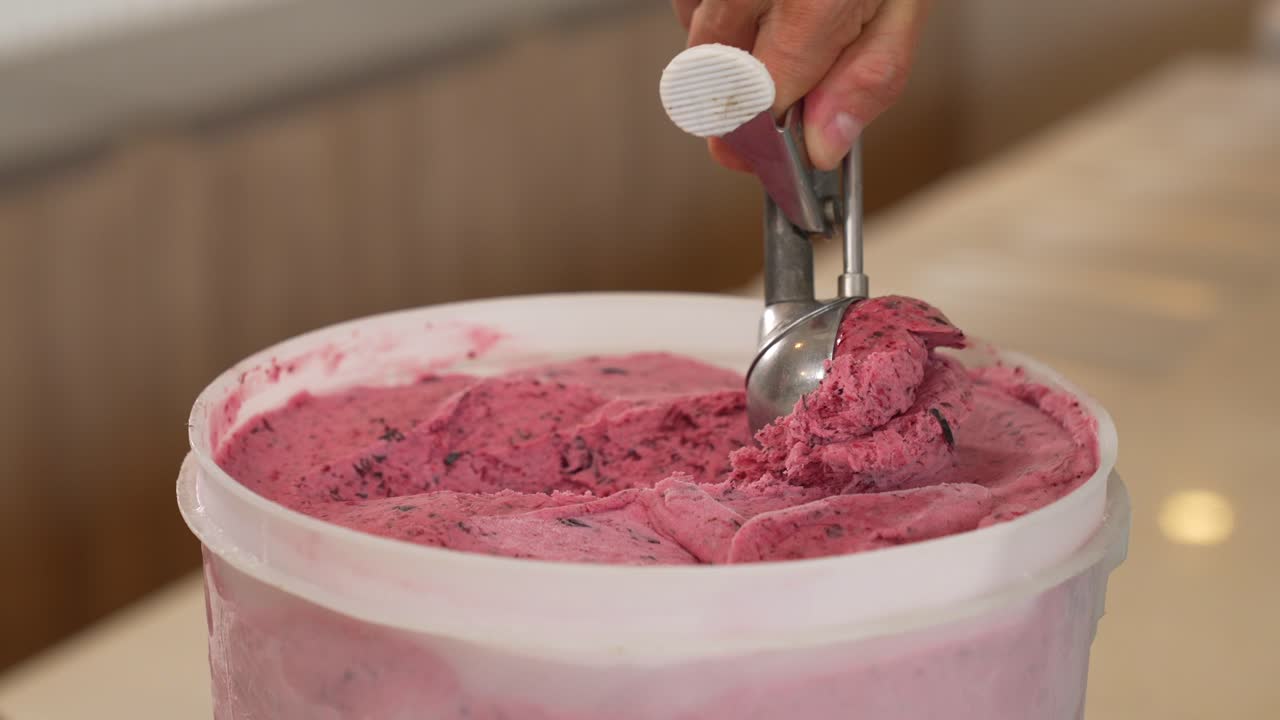 A female hand gracefully scoops and serves ice cream, illustrating the pleasure and delight of enjoying a sweet and cold dessert